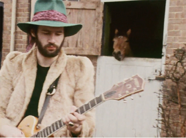 Neil Innes with guitar and horse.