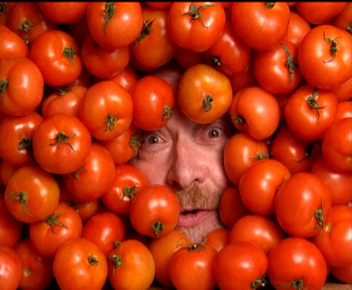 Face of the Reverend Lionel Fanthorpe peering out from tomatoes.